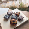 a collection of orange leopard pattern, white and black zebra stripe pattern and light pink with black leopard stripe apple airpods case kept on a book