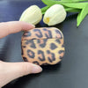 leopard textured, matte apple airpods third gen case showcased by female hand